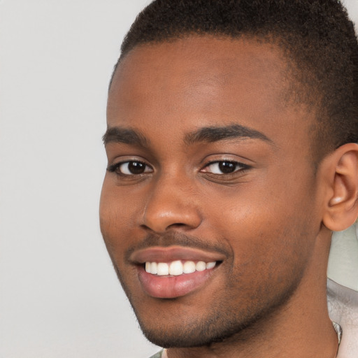 Joyful black young-adult male with short  brown hair and brown eyes