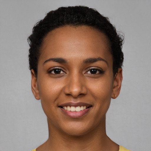 Joyful black young-adult female with short  black hair and brown eyes