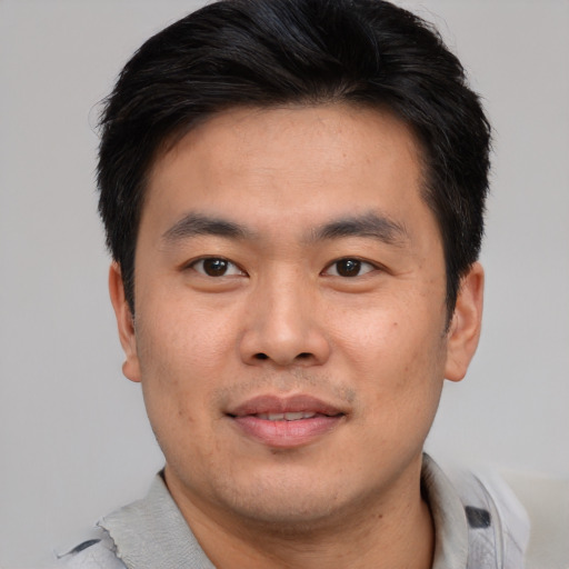 Joyful asian young-adult male with short  brown hair and brown eyes