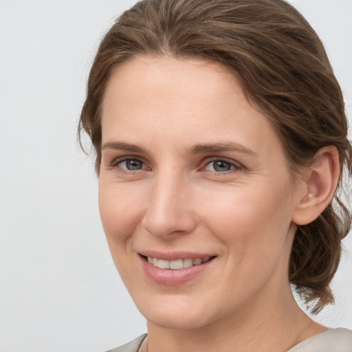 Joyful white young-adult female with medium  brown hair and grey eyes