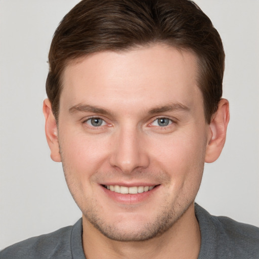 Joyful white young-adult male with short  brown hair and grey eyes