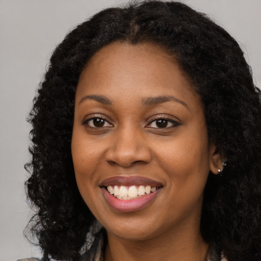 Joyful black young-adult female with long  brown hair and brown eyes