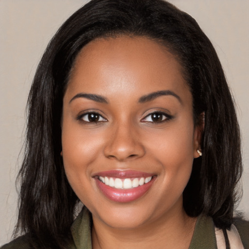 Joyful black young-adult female with long  brown hair and brown eyes