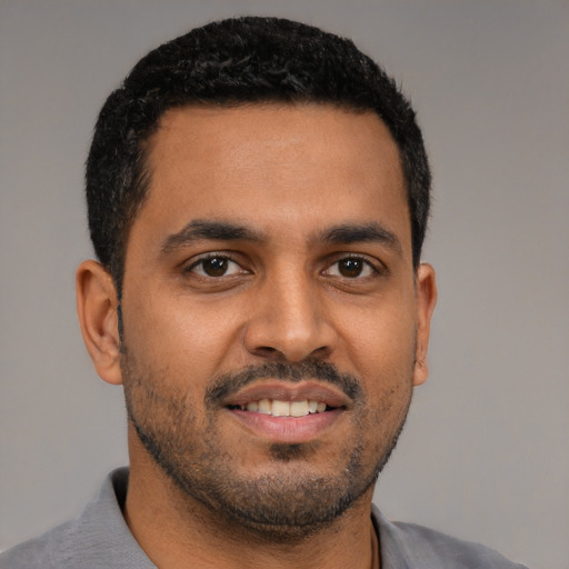 Joyful black young-adult male with short  black hair and brown eyes