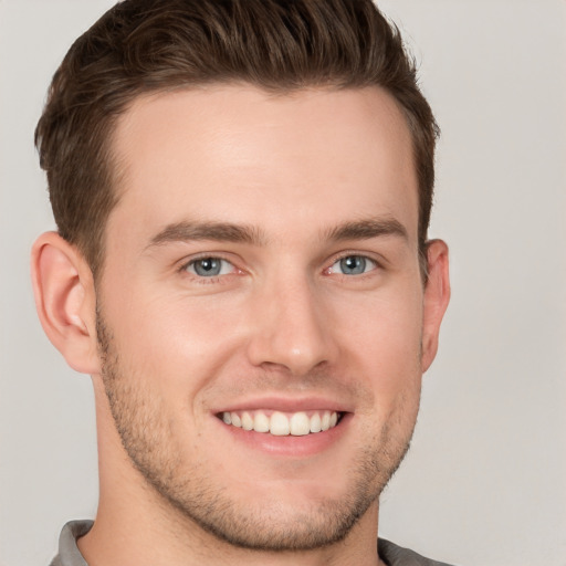 Joyful white young-adult male with short  brown hair and grey eyes