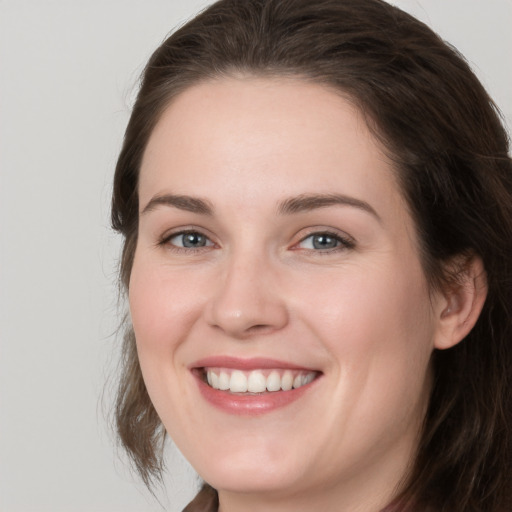 Joyful white young-adult female with medium  brown hair and grey eyes