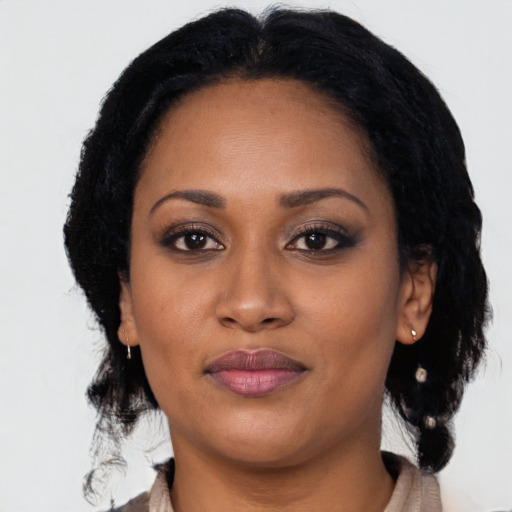 Joyful black young-adult female with long  black hair and brown eyes