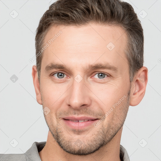 Joyful white young-adult male with short  brown hair and grey eyes