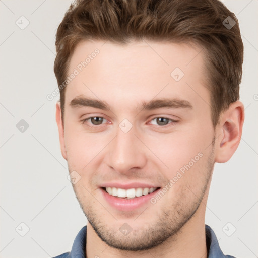 Joyful white young-adult male with short  brown hair and grey eyes