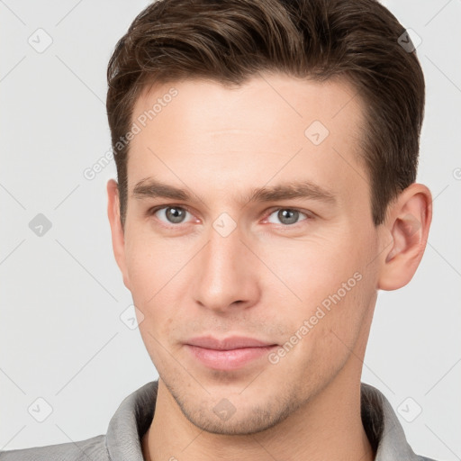 Joyful white young-adult male with short  brown hair and grey eyes