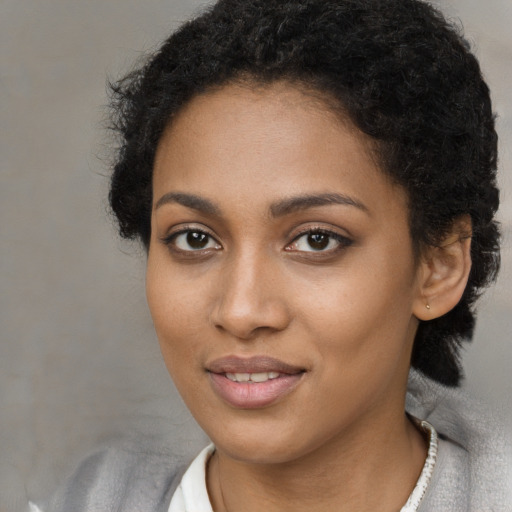 Joyful black young-adult female with short  black hair and brown eyes