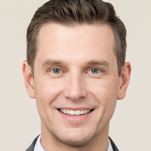 Joyful white young-adult male with short  brown hair and grey eyes