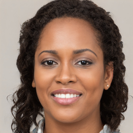 Joyful black young-adult female with long  brown hair and brown eyes