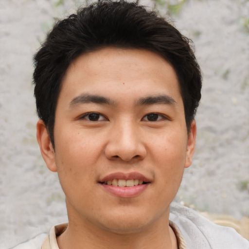 Joyful asian young-adult male with short  brown hair and brown eyes