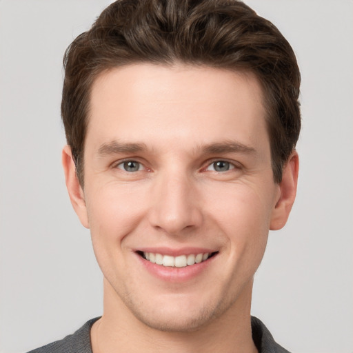 Joyful white young-adult male with short  brown hair and grey eyes