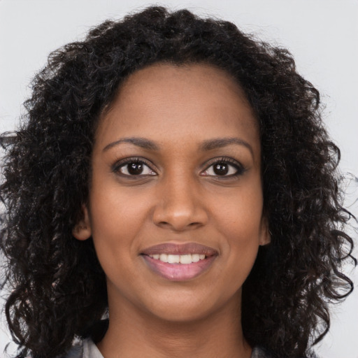 Joyful black young-adult female with long  brown hair and brown eyes