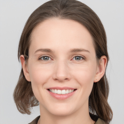 Joyful white young-adult female with medium  brown hair and grey eyes