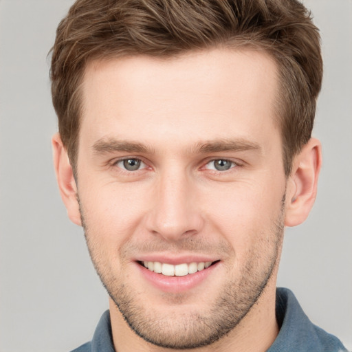 Joyful white young-adult male with short  brown hair and grey eyes