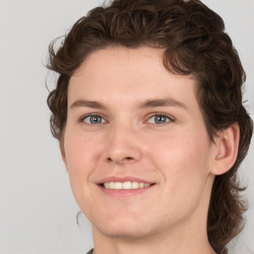 Joyful white young-adult male with medium  brown hair and grey eyes