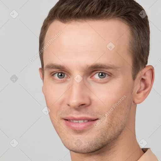 Joyful white young-adult male with short  brown hair and grey eyes