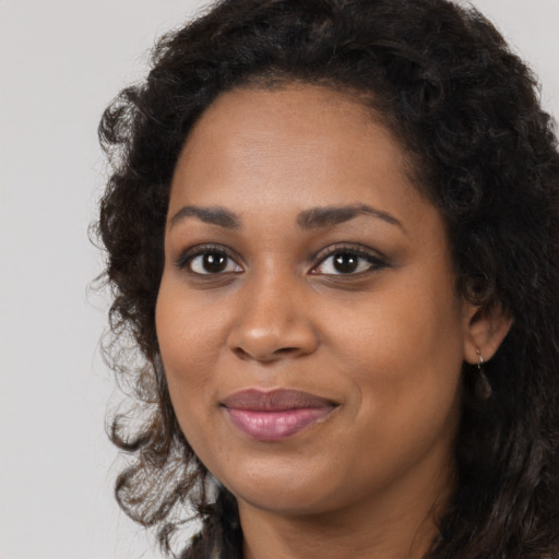 Joyful black young-adult female with long  brown hair and brown eyes