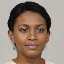 Joyful black young-adult female with short  black hair and brown eyes