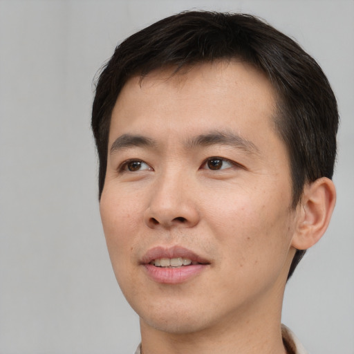 Joyful asian young-adult male with short  brown hair and brown eyes