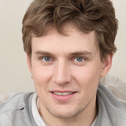 Joyful white young-adult male with short  brown hair and blue eyes