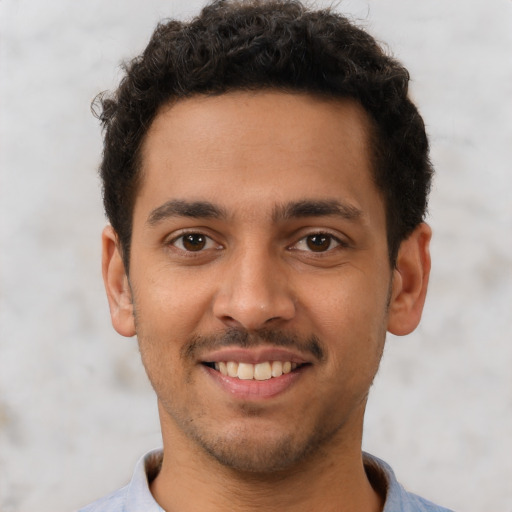 Joyful latino young-adult male with short  brown hair and brown eyes