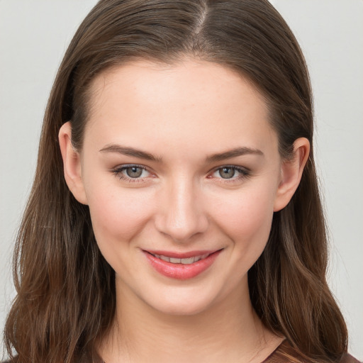 Joyful white young-adult female with long  brown hair and grey eyes