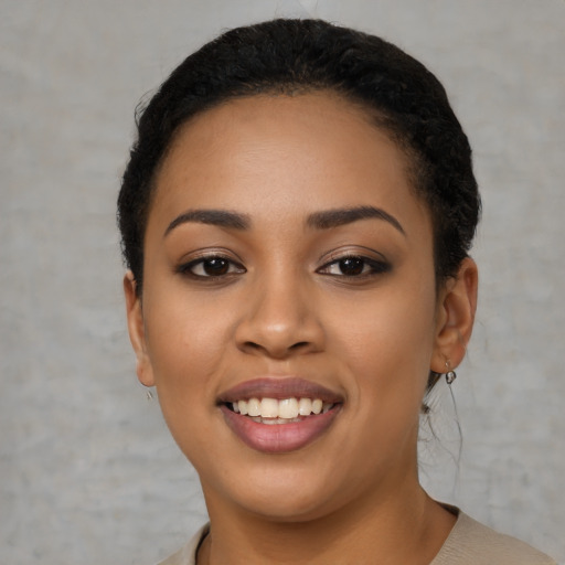 Joyful black young-adult female with short  black hair and brown eyes