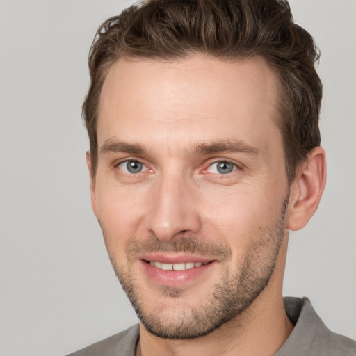 Joyful white young-adult male with short  brown hair and grey eyes