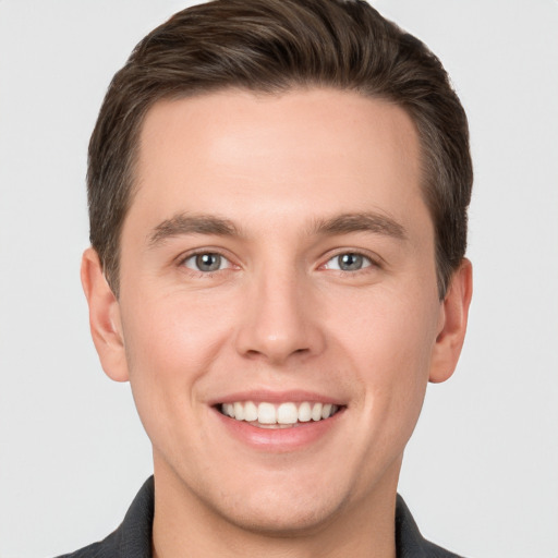 Joyful white young-adult male with short  brown hair and grey eyes