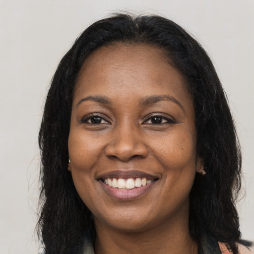 Joyful black young-adult female with long  brown hair and brown eyes