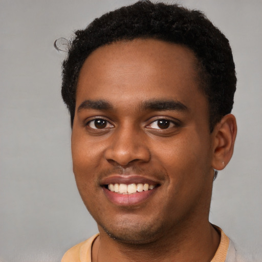 Joyful black young-adult male with short  brown hair and brown eyes
