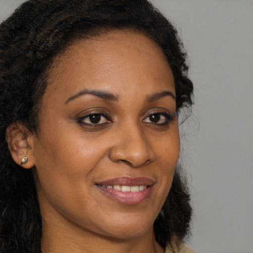 Joyful black young-adult female with long  brown hair and brown eyes