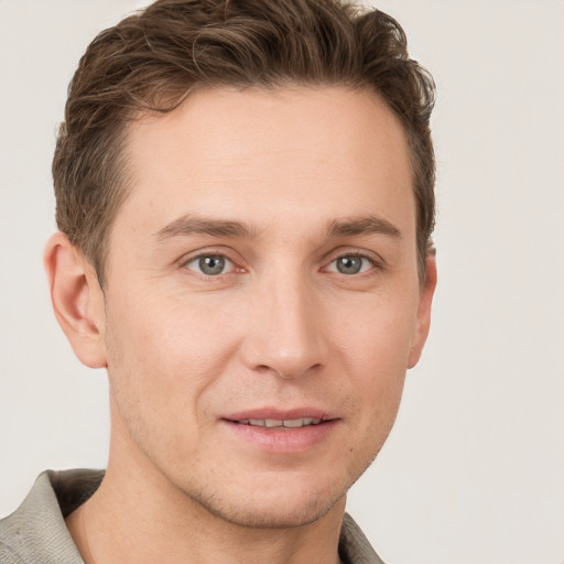 Joyful white young-adult male with short  brown hair and grey eyes