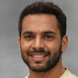 Joyful black young-adult male with short  brown hair and brown eyes