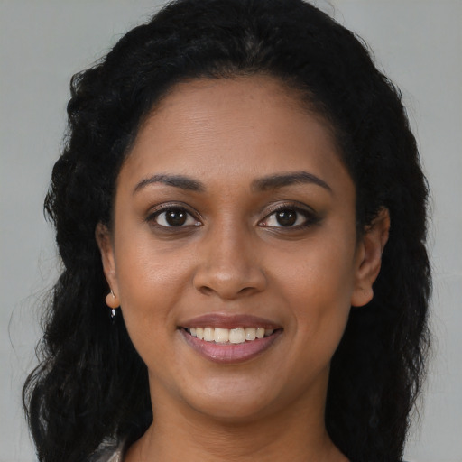 Joyful black young-adult female with long  brown hair and brown eyes