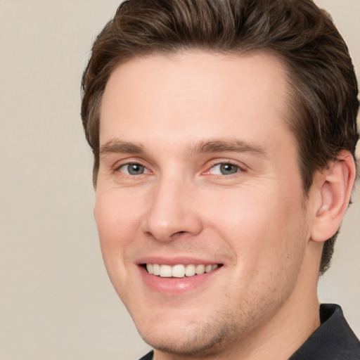 Joyful white young-adult male with short  brown hair and grey eyes