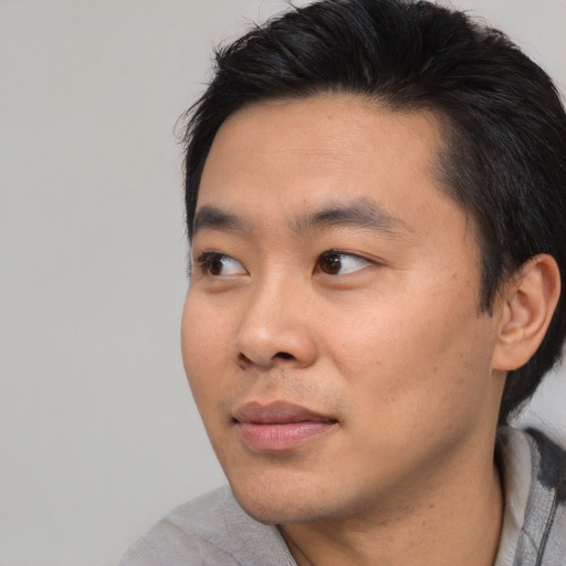 Joyful asian young-adult male with short  black hair and brown eyes