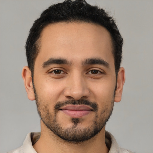 Joyful latino young-adult male with short  black hair and brown eyes