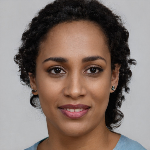 Joyful black young-adult female with long  brown hair and brown eyes