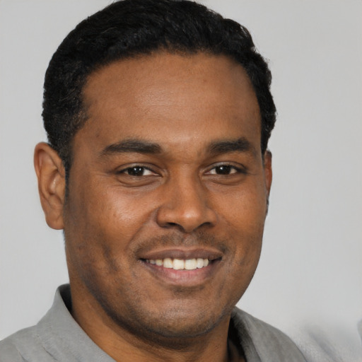 Joyful black young-adult male with short  black hair and brown eyes