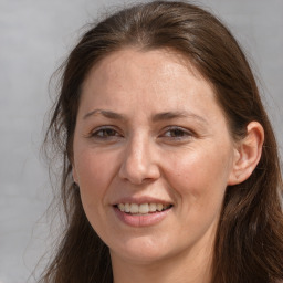 Joyful white adult female with long  brown hair and grey eyes