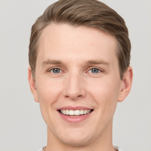 Joyful white young-adult male with short  brown hair and grey eyes