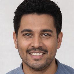 Joyful latino young-adult male with short  black hair and brown eyes