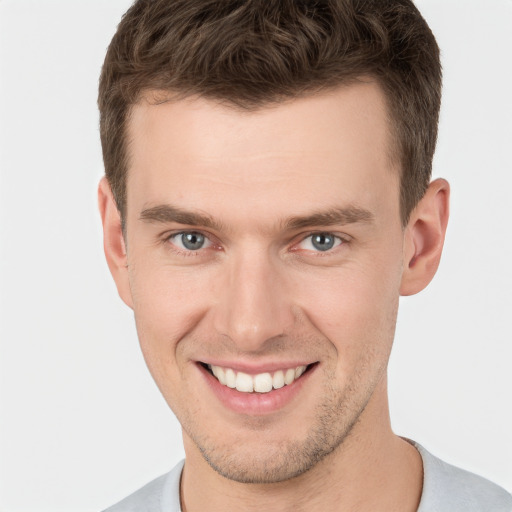 Joyful white young-adult male with short  brown hair and grey eyes