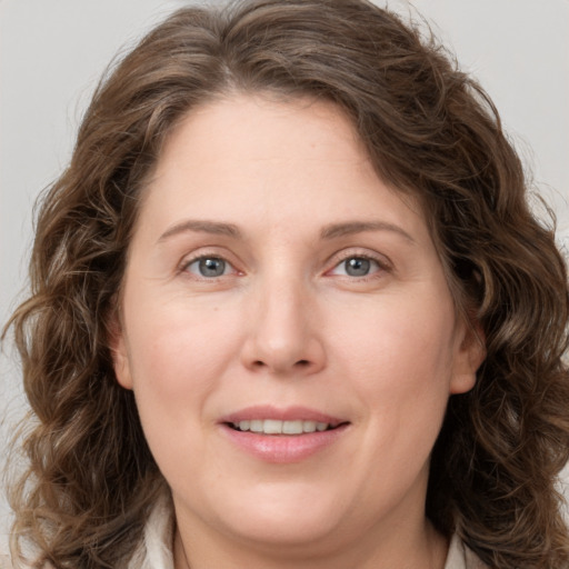 Joyful white adult female with long  brown hair and grey eyes