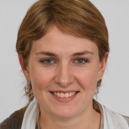 Joyful white young-adult female with medium  brown hair and grey eyes